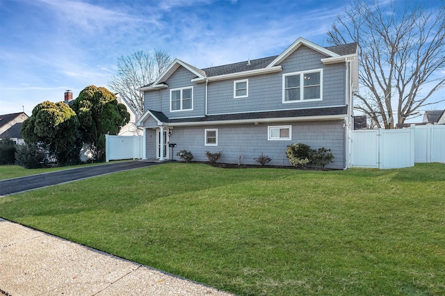 view of front of property featuring aphalt driveway, a front lawn, fence, and a gate