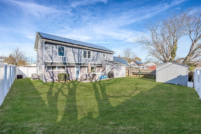 rear view of house with a storage shed, an outdoor structure, and a fenced backyard