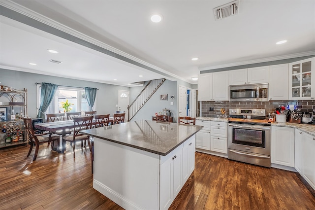 kitchen featuring decorative backsplash, visible vents, stainless steel appliances, and dark wood-type flooring