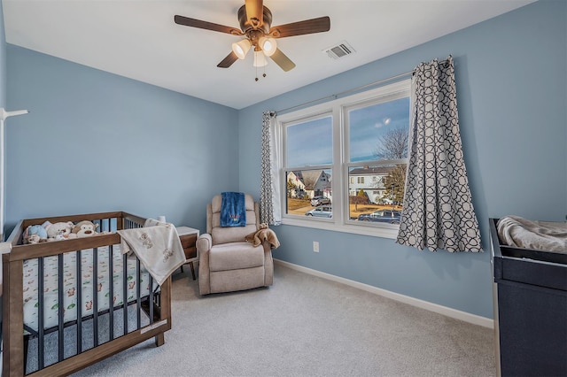 carpeted bedroom with a nursery area, baseboards, visible vents, and a ceiling fan