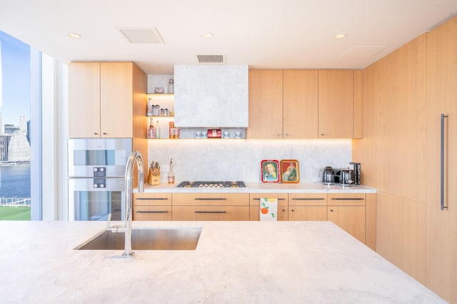 kitchen featuring stainless steel appliances, light brown cabinetry, sink, and backsplash