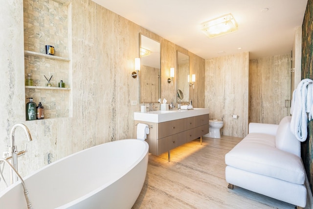 bathroom featuring vanity, toilet, hardwood / wood-style floors, and a washtub