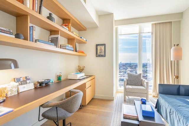 office with a healthy amount of sunlight, built in desk, and light hardwood / wood-style floors