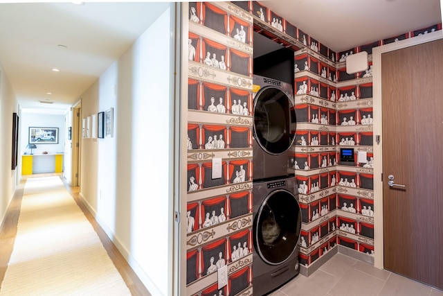 laundry area with stacked washing maching and dryer and tile patterned floors