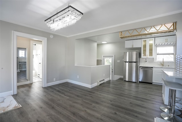 kitchen with baseboard heating, white cabinetry, backsplash, appliances with stainless steel finishes, and a healthy amount of sunlight