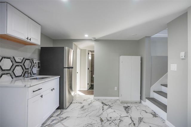 kitchen featuring sink, decorative backsplash, stainless steel refrigerator, and white cabinets