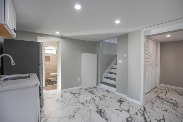 kitchen with light stone counters, sink, and white cabinets