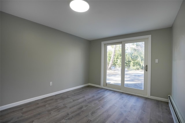 unfurnished room with a baseboard heating unit and hardwood / wood-style floors