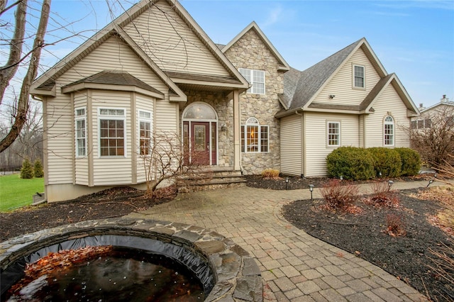 traditional-style home with stone siding and roof with shingles