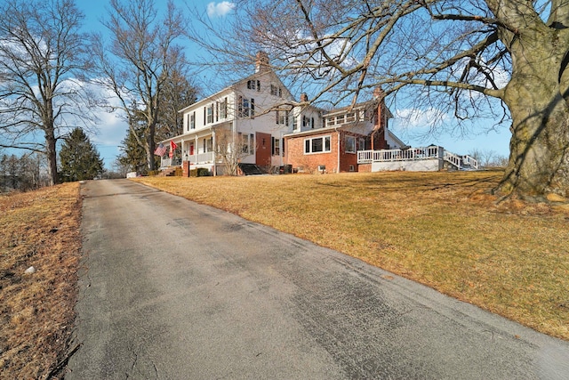 exterior space with brick siding, covered porch, a chimney, and a front lawn