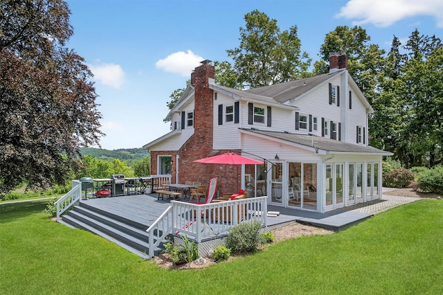 50 Maple Ave, Goshen, NY 10924 - rear view of house featuring a chimney, a sunroom, a deck, outdoor dining area, and a lawn