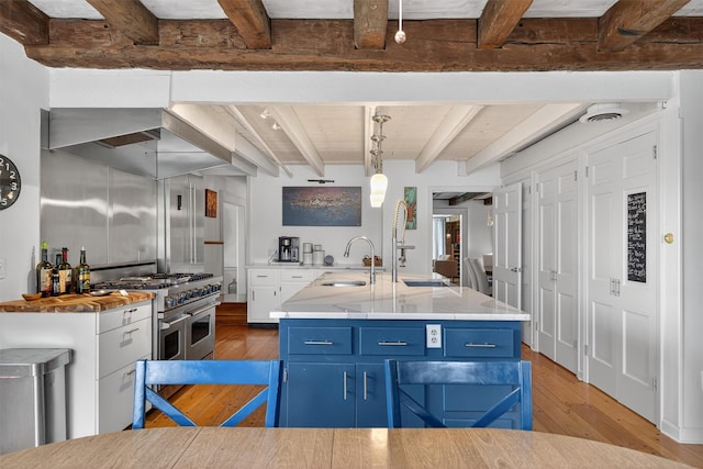 50 Maple Ave, Goshen, NY 10924 - kitchen with beam ceiling, double oven range, light wood-style floors, blue cabinetry, and hanging light fixtures
