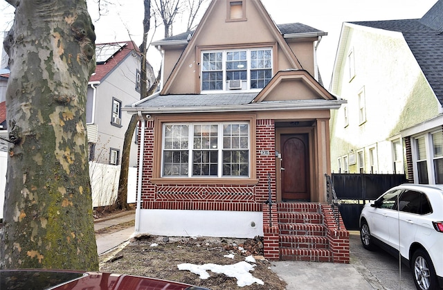 view of front of house with a shingled roof, entry steps, brick siding, and stucco siding