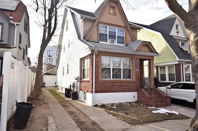 view of front of property with brick siding, roof with shingles, and fence