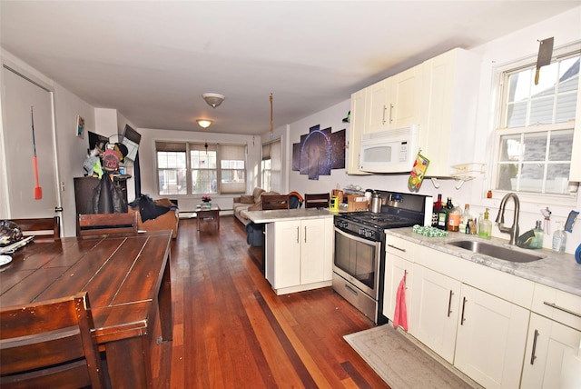 kitchen with white microwave, stainless steel range with gas stovetop, open floor plan, dark wood-type flooring, and a sink