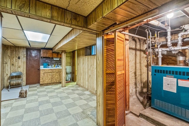 basement featuring wooden walls and a paneled ceiling