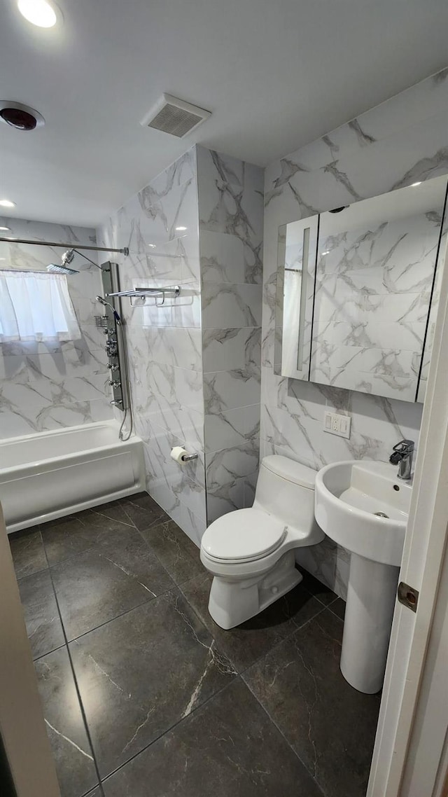 bathroom featuring tiled shower / bath combo, tile walls, and toilet