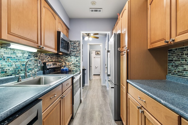 kitchen with sink, ceiling fan, appliances with stainless steel finishes, backsplash, and light hardwood / wood-style floors