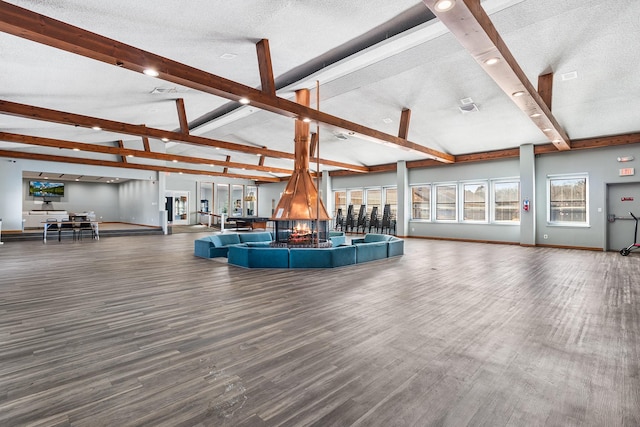 interior space with hardwood / wood-style floors, a textured ceiling, and vaulted ceiling with beams