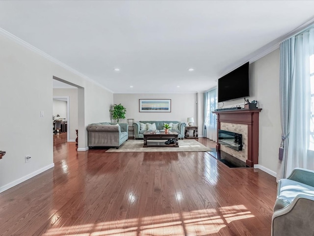 living area featuring ornamental molding, a fireplace with flush hearth, baseboards, and hardwood / wood-style flooring