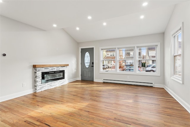 unfurnished living room featuring lofted ceiling, a baseboard heating unit, a stone fireplace, and light wood-type flooring