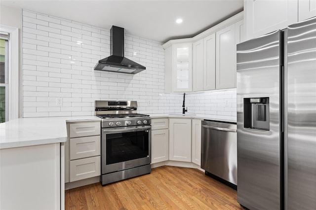 kitchen with white cabinetry, appliances with stainless steel finishes, and wall chimney exhaust hood