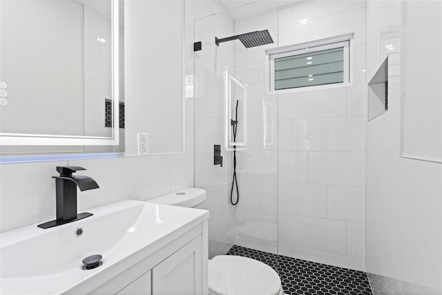 bathroom featuring tiled shower, vanity, toilet, and tile walls