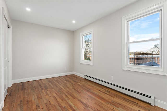 spare room featuring hardwood / wood-style flooring and a baseboard heating unit