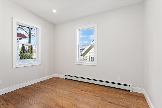 empty room featuring baseboard heating and light hardwood / wood-style floors