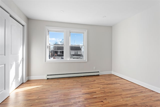 unfurnished bedroom featuring light hardwood / wood-style floors, a closet, and baseboard heating