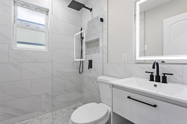 bathroom featuring vanity, a tile shower, tile walls, and toilet