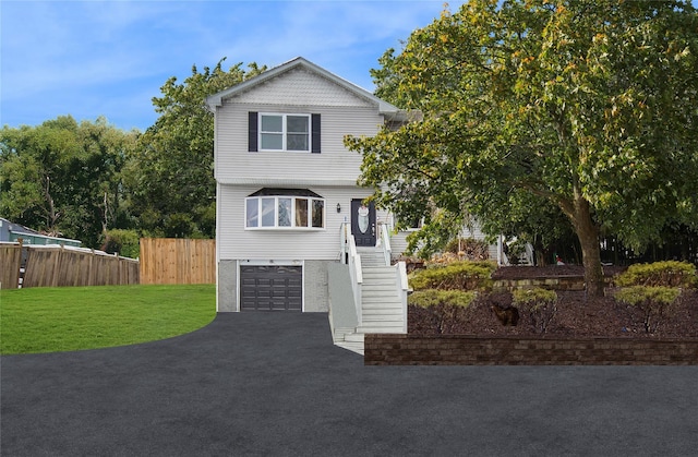 view of front of house featuring a garage, fence, driveway, stairway, and a front lawn