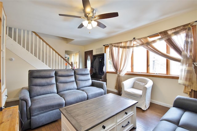 living area with stairway, baseboards, dark wood finished floors, and a ceiling fan