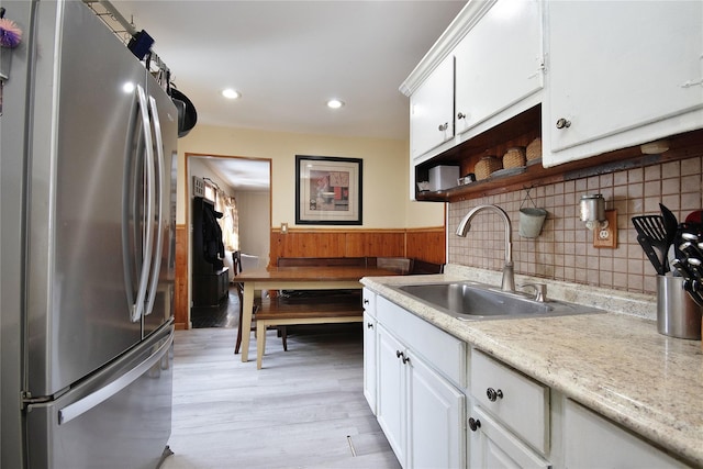 kitchen with light countertops, a sink, freestanding refrigerator, and white cabinets