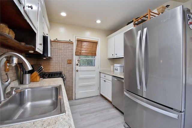 kitchen featuring white cabinets, stainless steel appliances, a sink, and light countertops