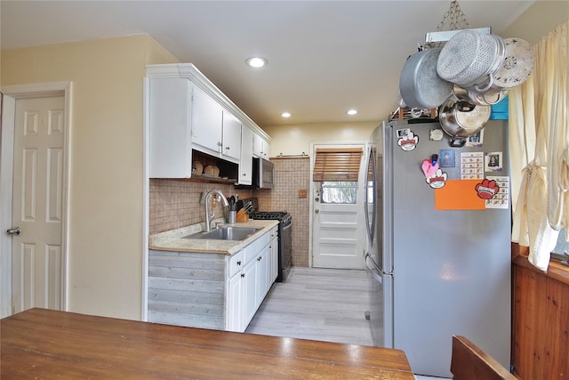 kitchen featuring appliances with stainless steel finishes, light countertops, a sink, and white cabinetry