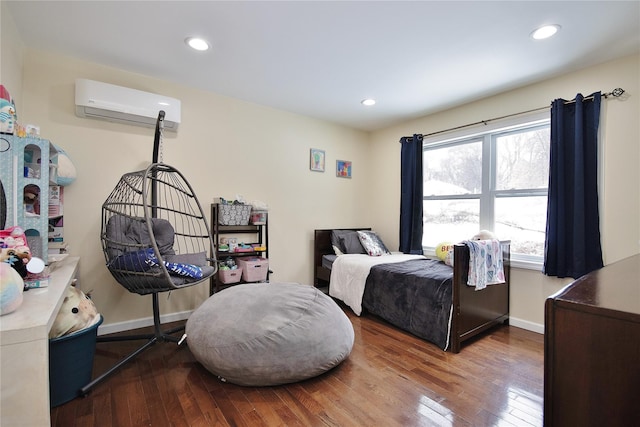 bedroom with an AC wall unit, wood-type flooring, and baseboards