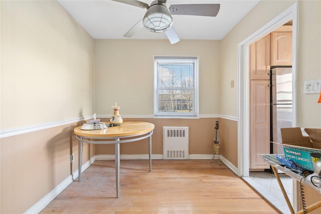 dining room featuring light wood-style floors, radiator heating unit, baseboards, and ceiling fan