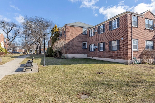 view of side of property with a lawn, a patio, a residential view, crawl space, and brick siding