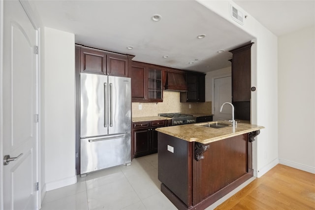 kitchen featuring custom exhaust hood, visible vents, backsplash, high quality fridge, and a sink