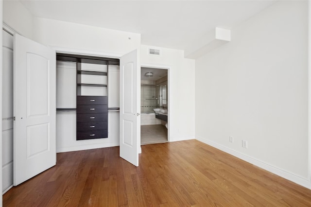 unfurnished bedroom with baseboards, a closet, visible vents, and wood finished floors