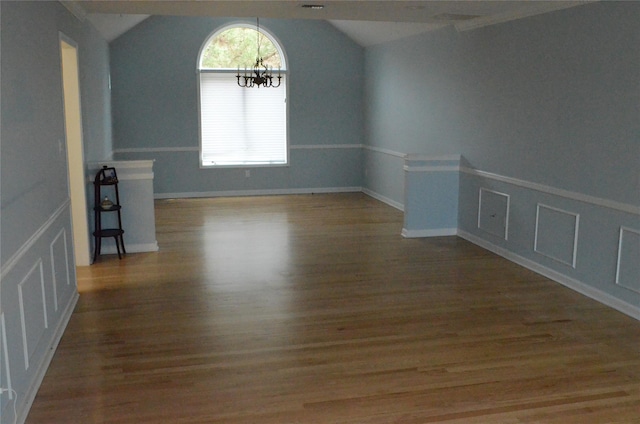 spare room with baseboards, lofted ceiling, wood finished floors, and a chandelier