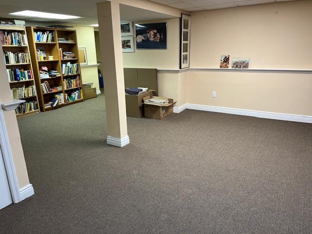 finished below grade area featuring baseboards, a drop ceiling, and carpet