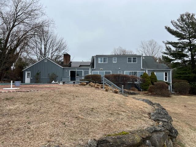 back of property with a chimney and roof mounted solar panels