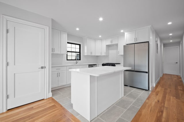 15815 77th Rd, Fresh Meadows, NY 11366 - kitchen featuring light countertops, backsplash, freestanding refrigerator, a center island, and white cabinets