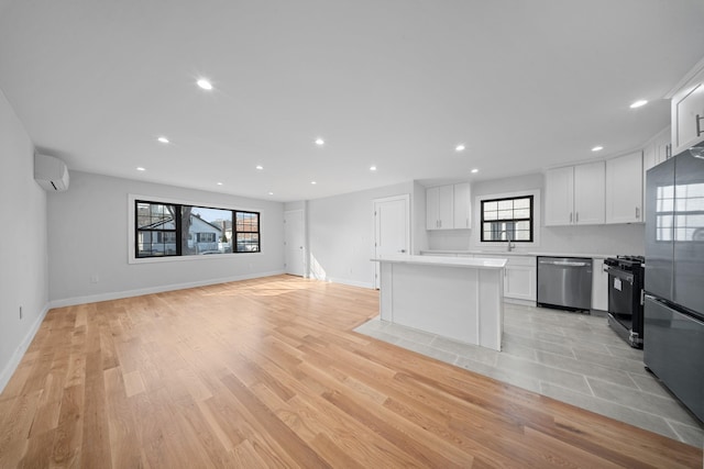 15815 77th Rd, Fresh Meadows, NY 11366 - kitchen with light countertops, a wall unit AC, light wood finished floors, white cabinets, and appliances with stainless steel finishes