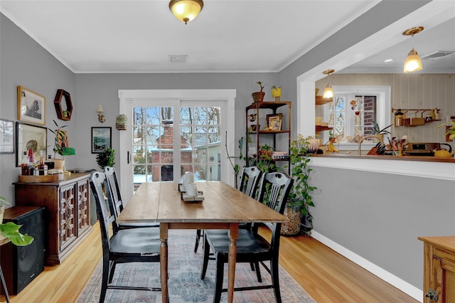 dining area with ornamental molding and light wood-type flooring