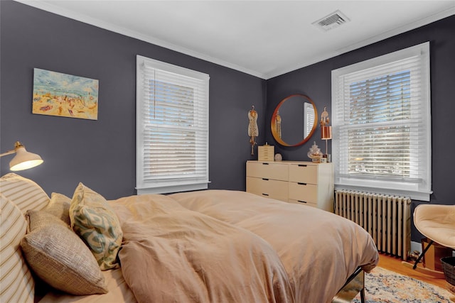 bedroom featuring hardwood / wood-style floors, crown molding, and radiator heating unit