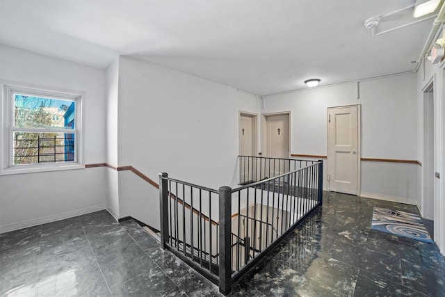 hallway with an upstairs landing and baseboards