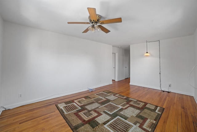 unfurnished room with a ceiling fan, wood-type flooring, and baseboards